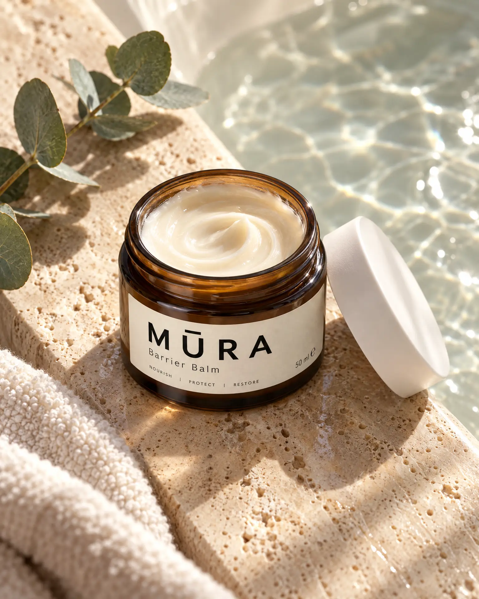 An open amber jar of barrier balm on the edge of a travertine bath in rippling water light.
