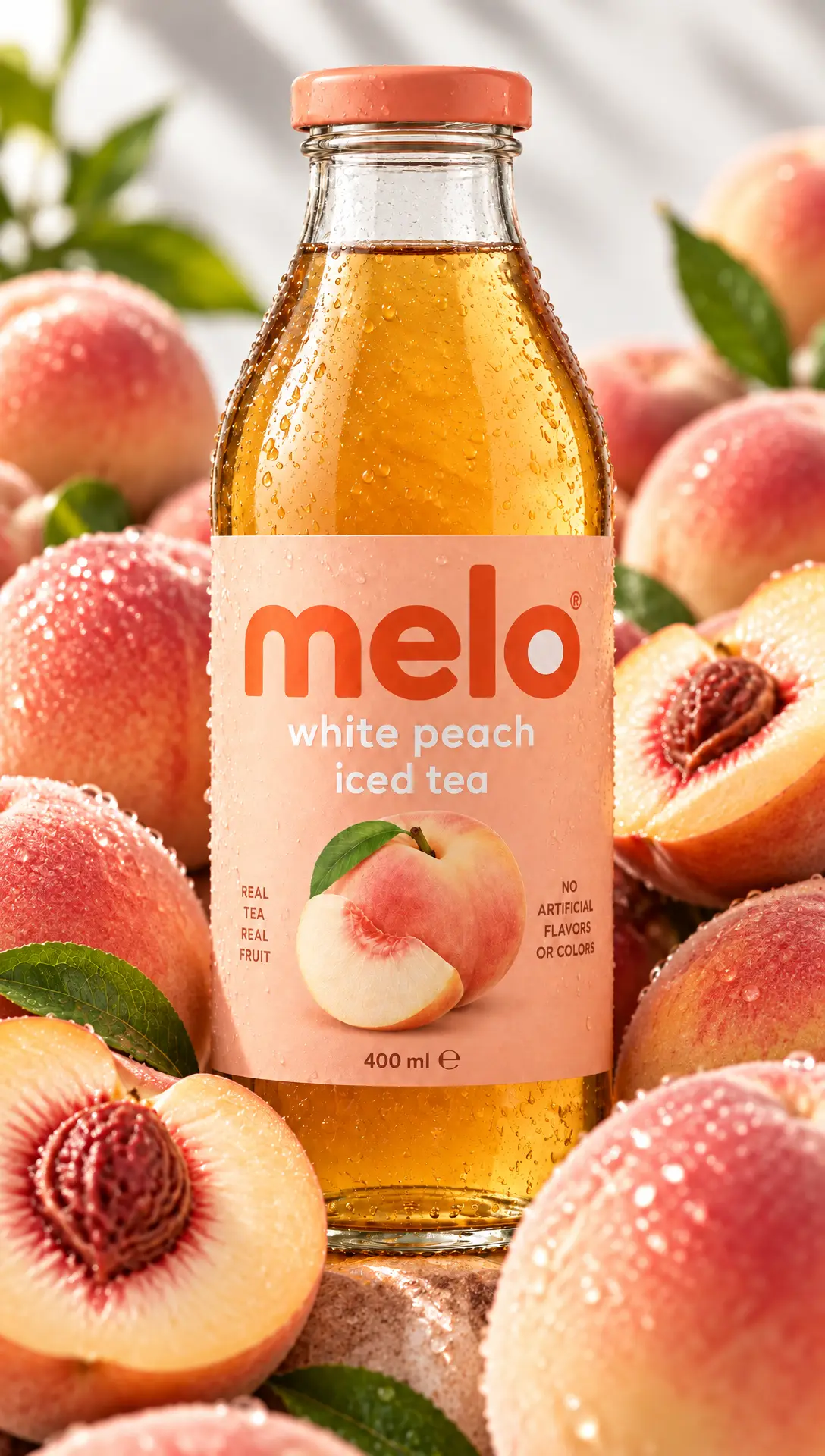 A Melo white peach iced tea bottle among ripe and halved peaches.